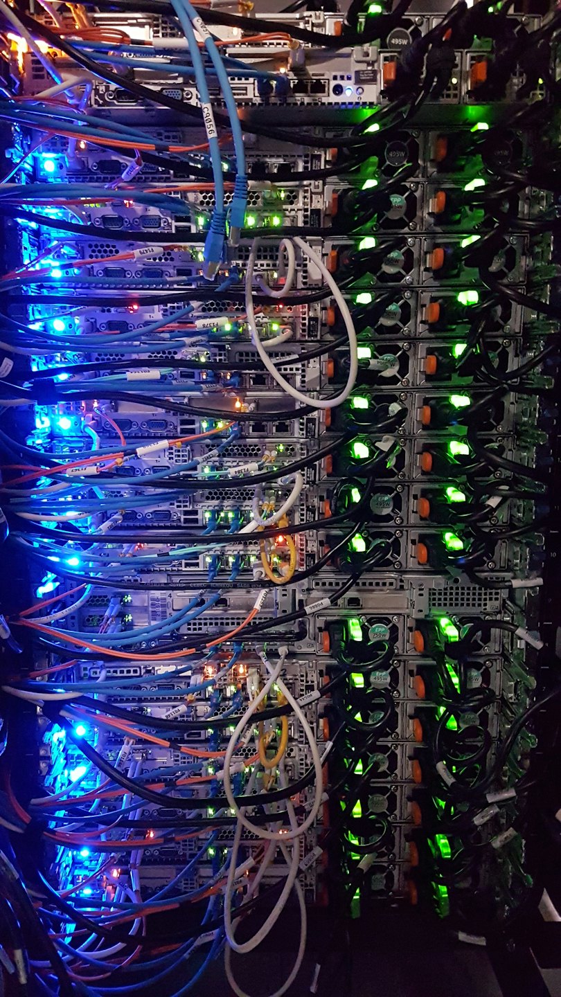 Rack de servere cu multe cabluri colorate și lumini strălucitoare.